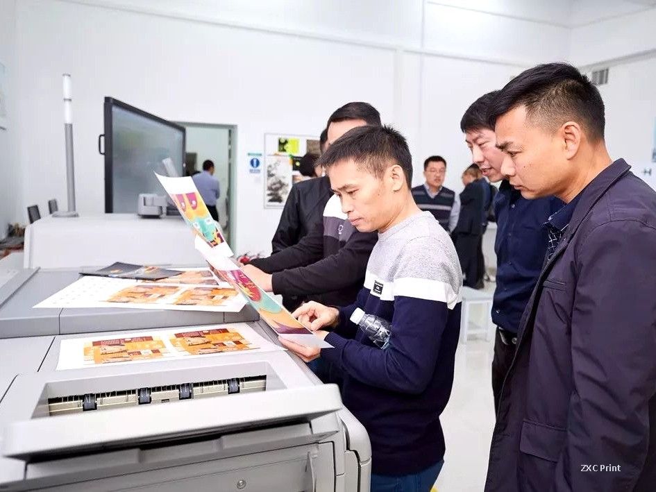 Print shop workers inspecting freshly printed sheets for ink fill-in defects