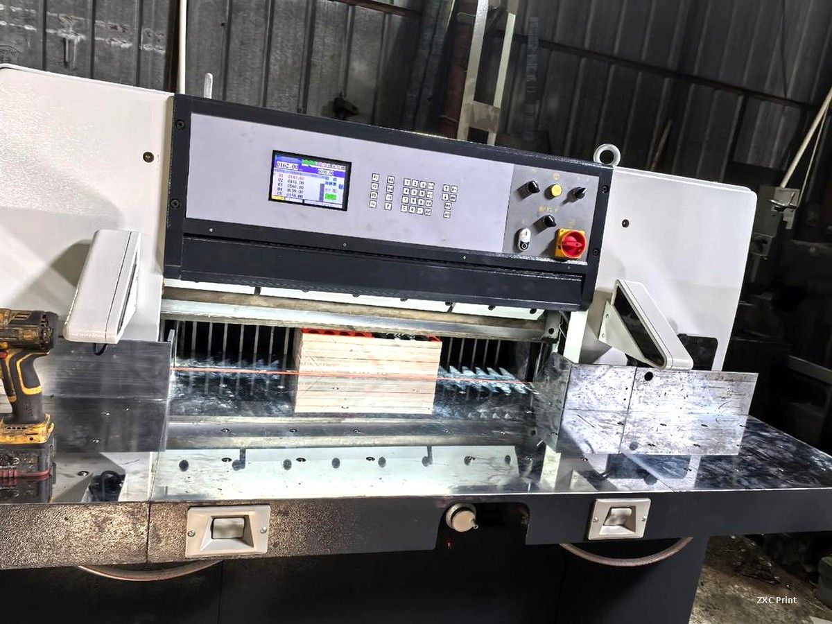 Guillotine paper cutter trimming a stack of coated paper