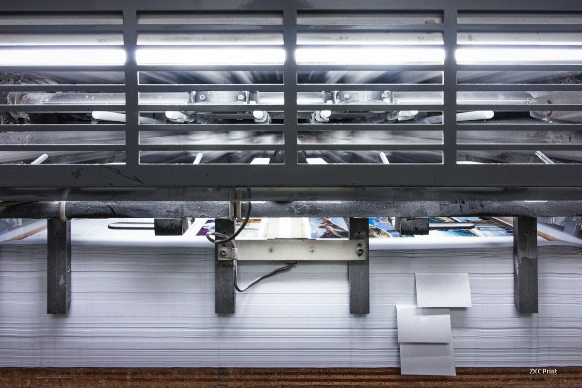Delivery end of a modern printing press with a neat stack of freshly printed sheets